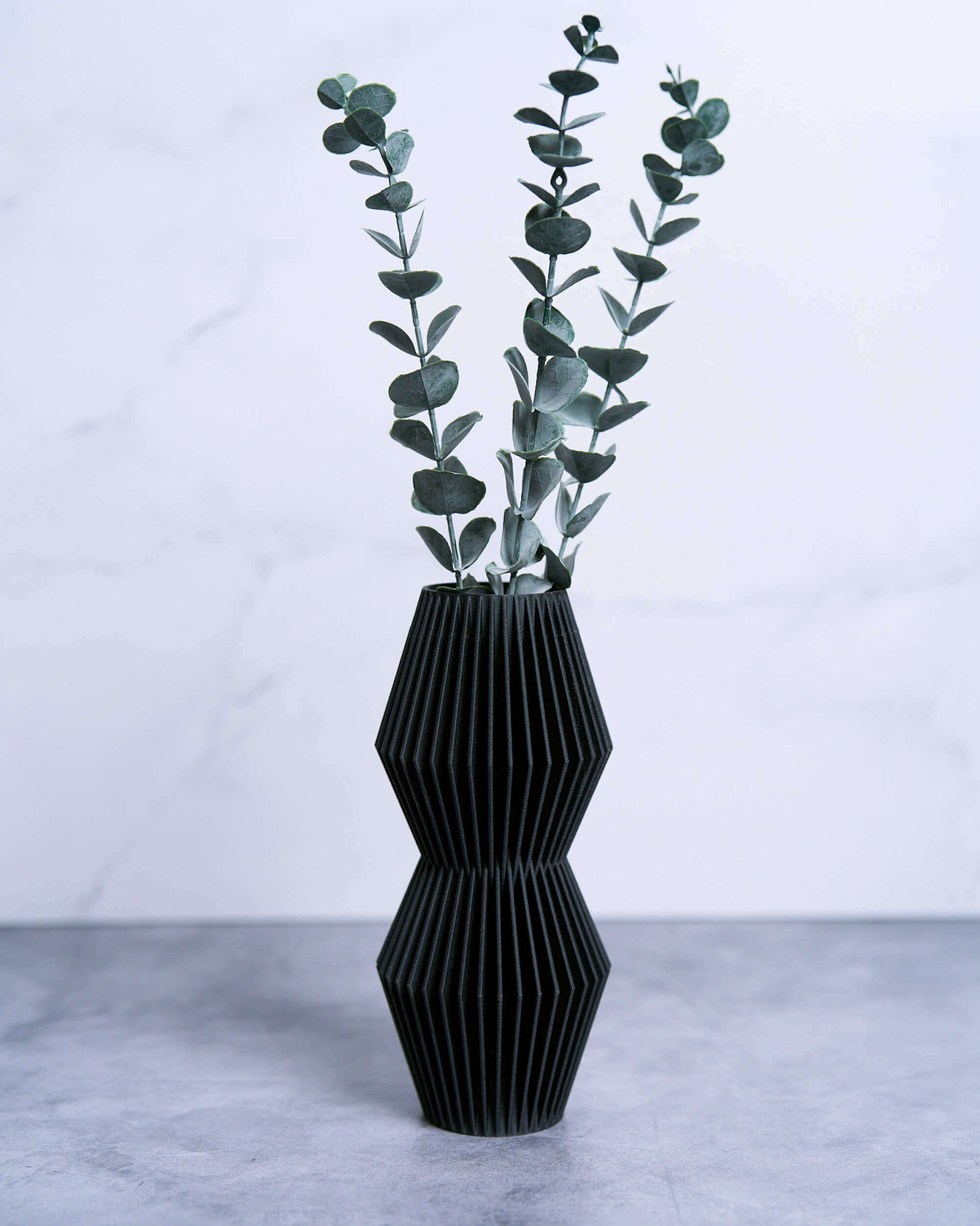 A black vase with eucalyptus. This is a modernist vase from Woodland Pulse's unique vases collection. This is a small vase.