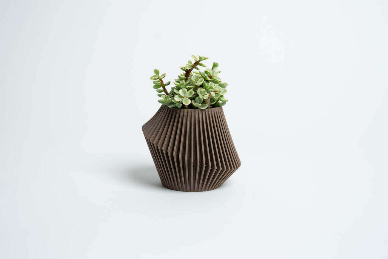 A small size DISC boho planter by Woodland Pulse. This is a brown small succulent pot with a green succulent inside.