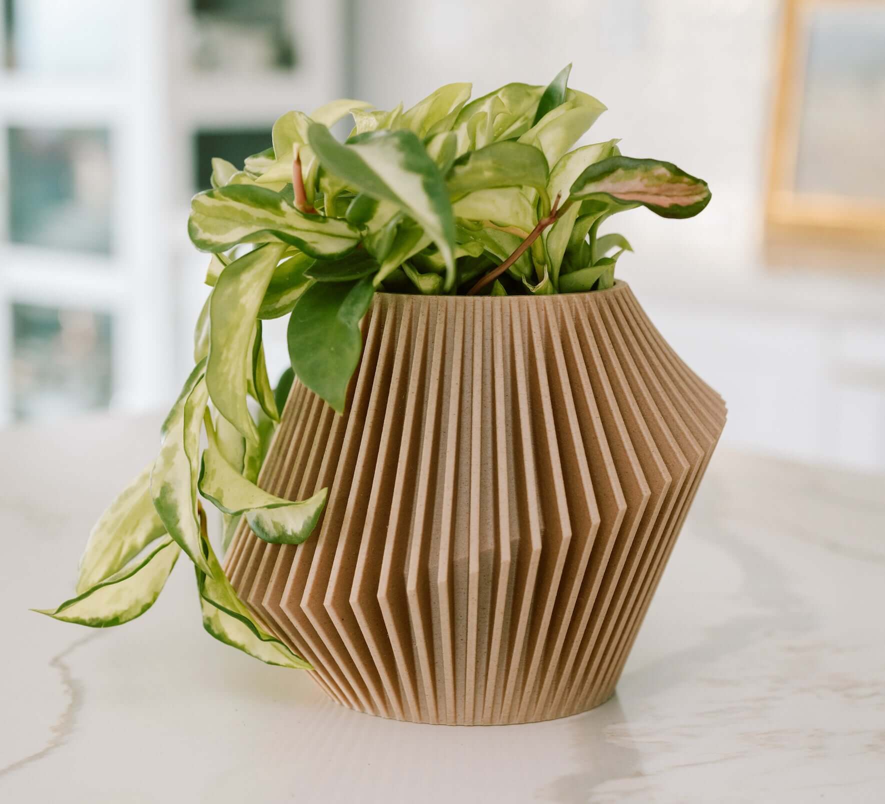 Woodland Pulse modern planter infused with cedar oil, DISC, in beige on a white marble countertop.