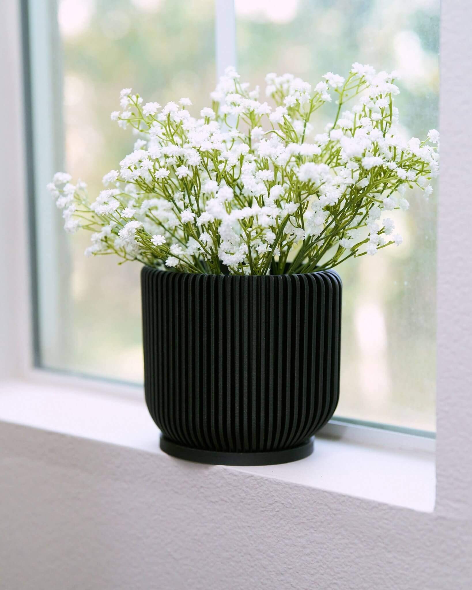 IONIC black flower pot with flowers by Woodland Pulse.