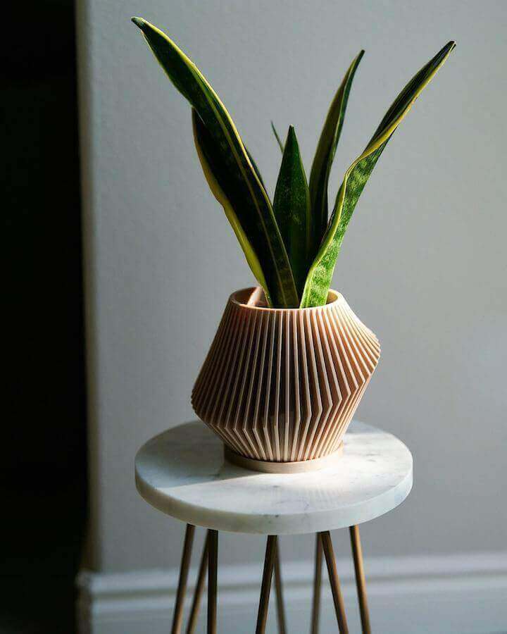 Woodland Pulse's best-seller planter diffuser, DISC, on a white marble side table. This is a beige cedar oil infused planter.