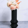 A black modernist vase by Woodland Pulse. This is a black vase / unique case with white and pink flowers.