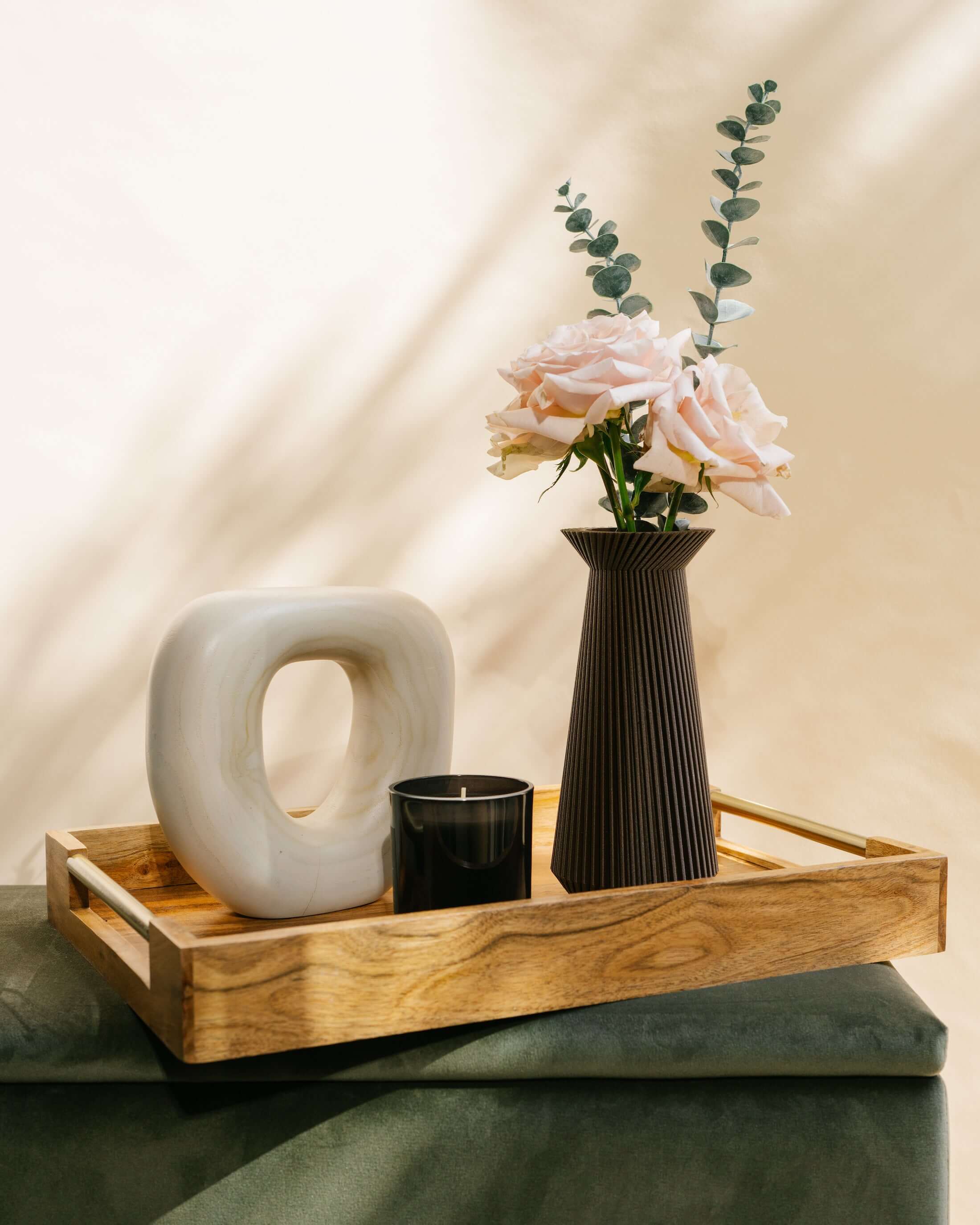 The BANDA brown vase with flowers and eucalyptus, a candle, and accent decor.
