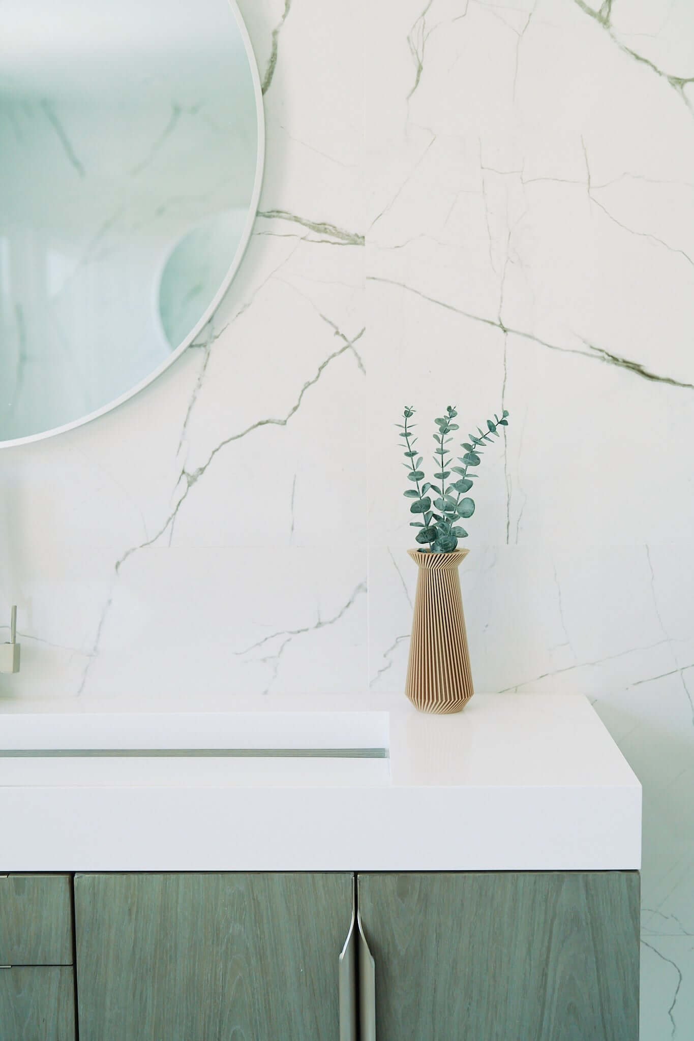 A boho vase / beige vase with eucalyptus on a marble bathroom sink countertop. This is from unique vases of Woodland Pulse.