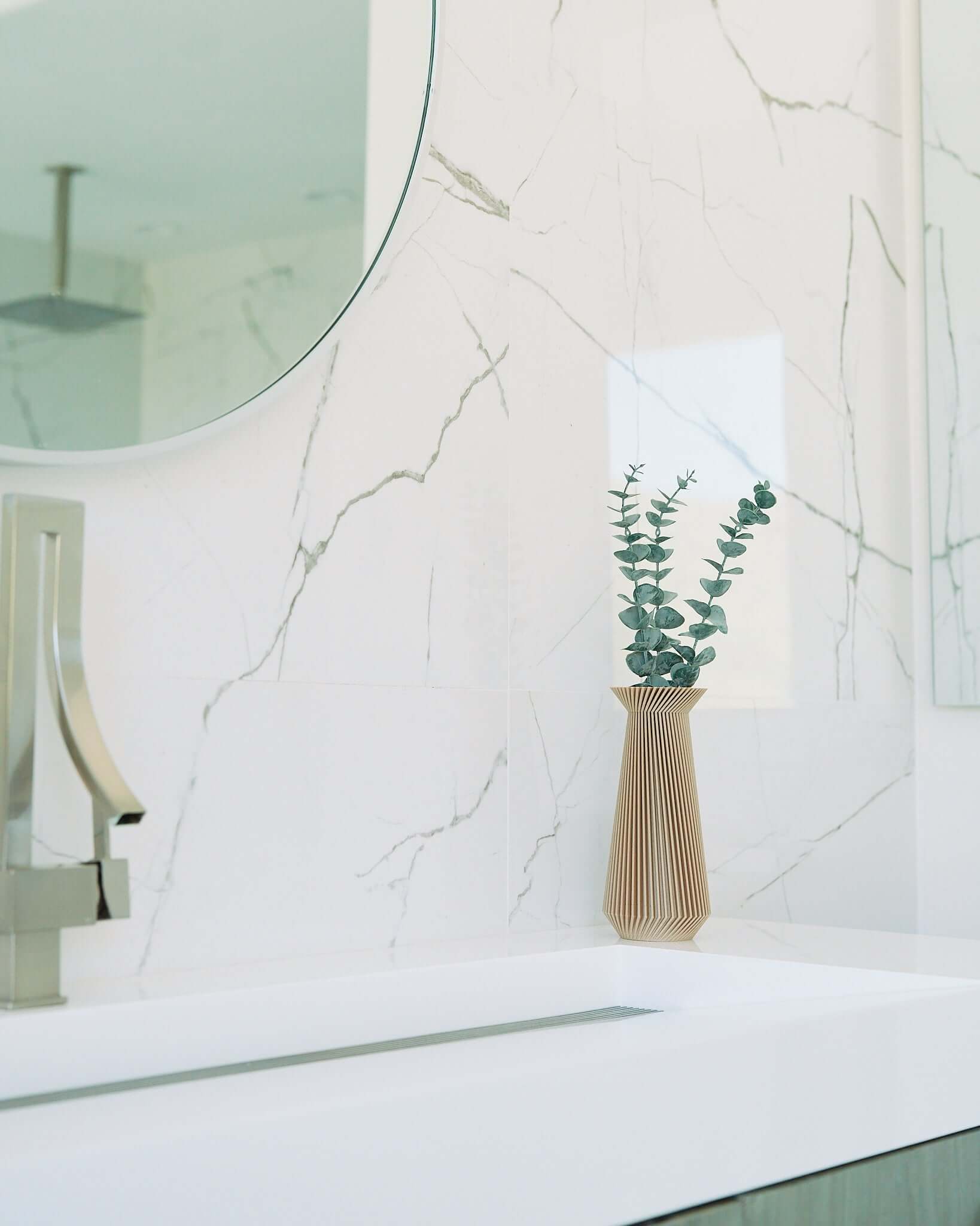 A cream vase with eucalyptus by Woodland Pulse. This is a modernist vase on a bathroom sink marble countertop.