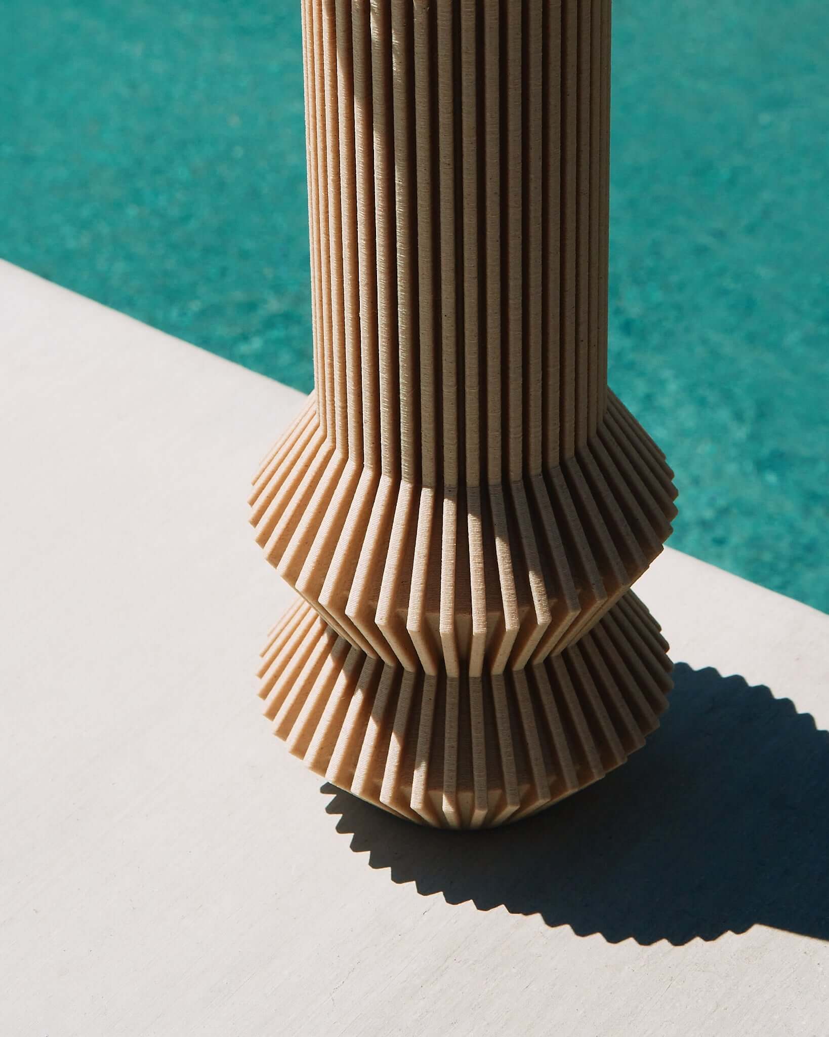 A beige vase from Woodland Pulse near a pool. 