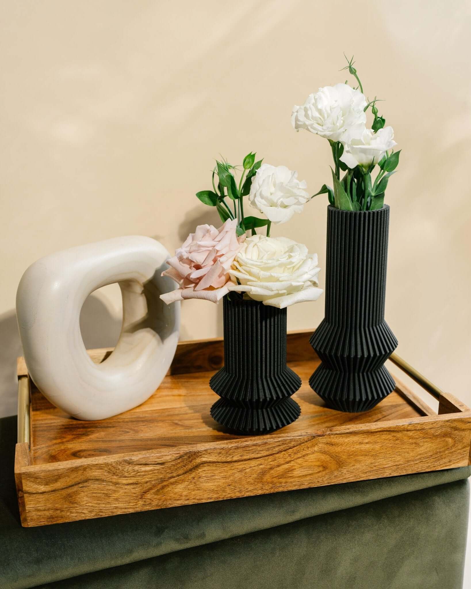 Two small black vases with flowers.